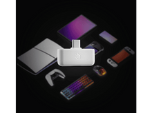 Charger l&#39;image dans la galerie, Adaptateur blanc, divers appareils flous en arrière-plan. Périphériques de jeu, téléphone et console visibles.
