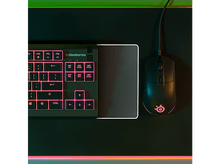 Charger l&#39;image dans la galerie, Clavier et souris noirs sur un tapis de souris noir, éclairés par des lumières roses.
