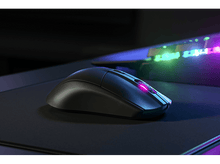 Charger l&#39;image dans la galerie, Souris de jeu noire sur un tapis de souris. La souris a une lumière rose brillante.
