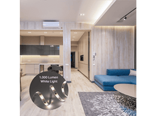 Charger l&#39;image dans la galerie, Salon moderne avec cuisine ouverte. Canapé bleu, planchers en bois, table ronde et tapis. Bande lumineuse blanche affichée.
