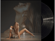 Charger l'image dans la galerie, Femme assise par terre avec un disque vinyle. Une photo est en arrière-plan.
