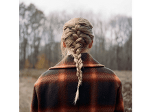 Charger l&#39;image dans la galerie, Dos d&#39;une femme, avec une longue tresse blonde. Vêtue d&#39;une veste à carreaux, debout dans un champ flou.
