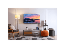 Charger l'image dans la galerie, Salon avec une TV au mur, une lampe et un tapis à motifs.
