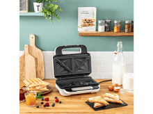 Charger l&#39;image dans la galerie, Appareil à sandwich sur une table en bois. Gaufres, confiture, fruits et lait sont sur la table.
