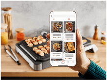 Charger l&#39;image dans la galerie, Une main tenant un smartphone affichant une application de recettes avec diverses images de plats.
