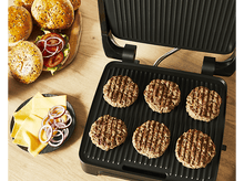 Charger l&#39;image dans la galerie, Un grill noir avec des burgers cuits, du fromage, des oignons tranchés et des pains sur une surface en bois.
