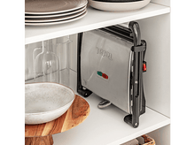 Charger l&#39;image dans la galerie, Un grill Tefal argent plié à l&#39;intérieur d&#39;un meuble blanc. Des plats sur l&#39;étagère.
