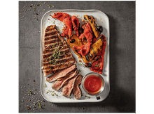 Charger l&#39;image dans la galerie, Une assiette avec du steak grillé, des poivrons rôtis, des olives et un petit bol de sauce. Garnie d&#39;herbes.

