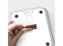 Charger l'image dans la galerie, Une main insérant des piles dans une balance blanche.
