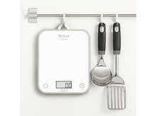 Charger l'image dans la galerie, Balance de cuisine blanche, cuillères doseuses et spatule suspendues à une barre métallique sur mur blanc.
