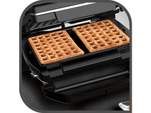 Charger l&#39;image dans la galerie, Deux gaufres dorées dans un gaufrier noir. La machine est ouverte, les gaufres sont prêtes à être mangées.
