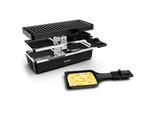 Charger l&#39;image dans la galerie, Gril à raclette noir avec fromage dans une poêle. Premier plan : poêle noire, arrière-plan : surface noire.
