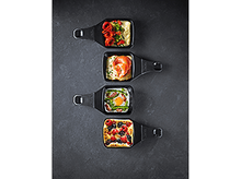 Charger l&#39;image dans la galerie, Quatre petites poêles à raclette noires avec des aliments cuits, disposées sur une surface sombre.
