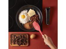 Charger l&#39;image dans la galerie, Des ingrédients pour la pâtisserie sont disposés sur une table de cuisson noire, à côté d&#39;une cuillère rouge.
