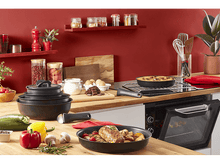Charger l&#39;image dans la galerie, Scène de cuisine avec des aliments en cours de cuisson. Poêles, épices, légumes et un fond rouge.
