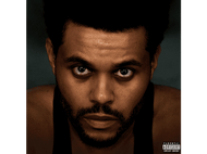 Gros plan sur le visage d'un homme, regard intense. Fond sombre, débardeur noir. The Weeknd.