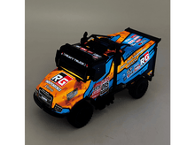 Charger l&#39;image dans la galerie, Camion jouet coloré avec multiples autocollants, orange et bleu, avec toit noir et grandes roues.
