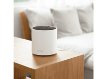 Charger l&#39;image dans la galerie, Un routeur blanc sur une table en bois devant un lit.
