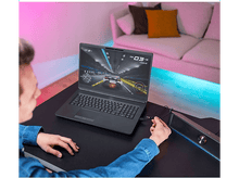 Charger l&#39;image dans la galerie, Une personne utilisant un ordinateur portable avec un jeu de course sur l&#39;écran, connecté à un haut-parleur.
