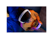 Charger l&#39;image dans la galerie, Personne portant un casque blanc, tenant une manette, dans une pièce à éclairage bleu et violet.
