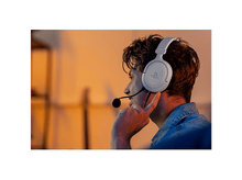 Charger l&#39;image dans la galerie, Homme portant un casque de jeu blanc, regardant à droite, dans une pièce éclairée en orange.
