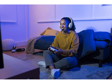 Charger l&#39;image dans la galerie, Femme joue avec casque et manette. Chambre avec lit, lumières bleues/violettes.

