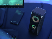 Charger l&#39;image dans la galerie, Haut-parleur, moniteur et téléphone sur un bureau bleu foncé. Effets d&#39;éclairage colorés.
