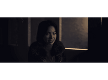 Charger l&#39;image dans la galerie, Une femme aux cheveux noirs regardant la caméra, avec un léger froncement de sourcils.
