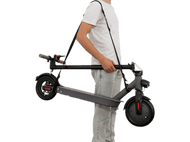 Une personne tenant une trottinette noire pliée par une sangle. La trottinette est grise et noire.