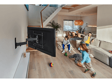 Charger l&#39;image dans la galerie, Salon avec une TV murale. Une famille est dans la pièce, un enfant joue.
