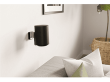 Charger l&#39;image dans la galerie, Un haut-parleur noir monté sur un mur blanc avec un support noir et une plante.
