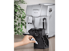 Charger l&#39;image dans la galerie, Une main applique de la graisse sur un composant de cafetière sur une table.
